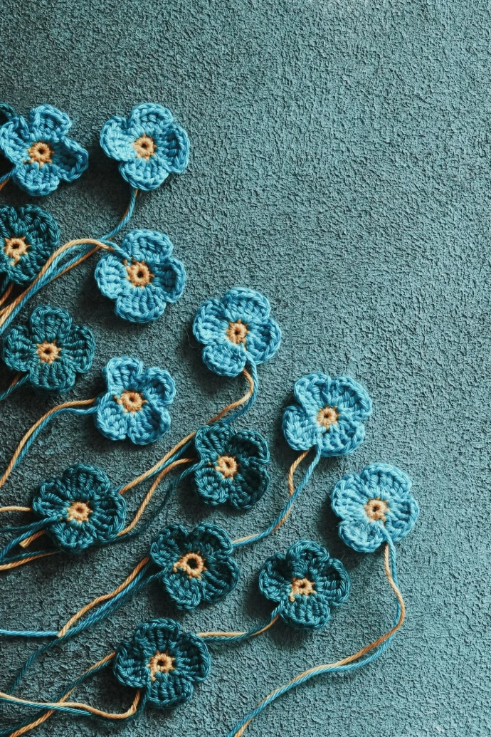 a group of crocheted flowers sitting on a blue surface
