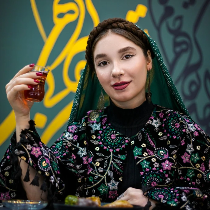 Woman in traditional attire holds tea.