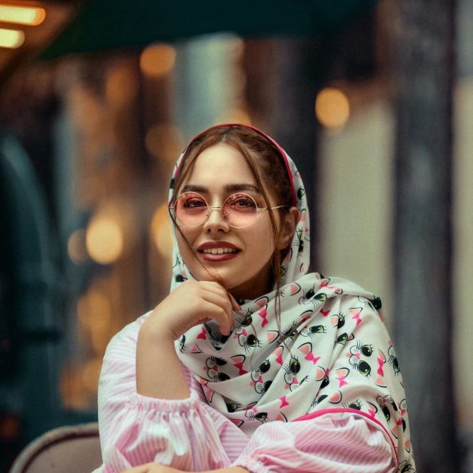 a woman wearing a pink and white scarf and glasses